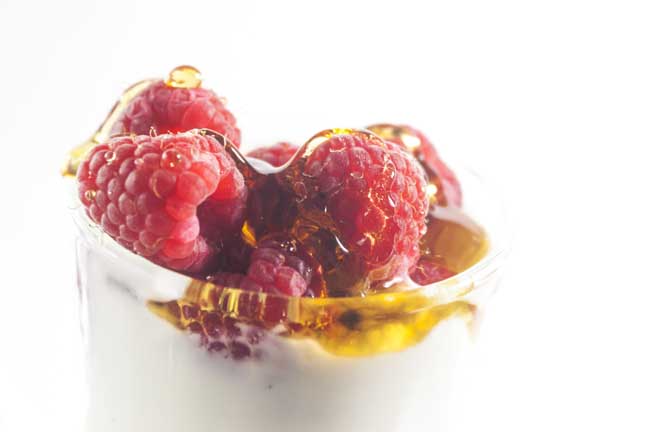 Raspberries and honey in a glass of yogurt