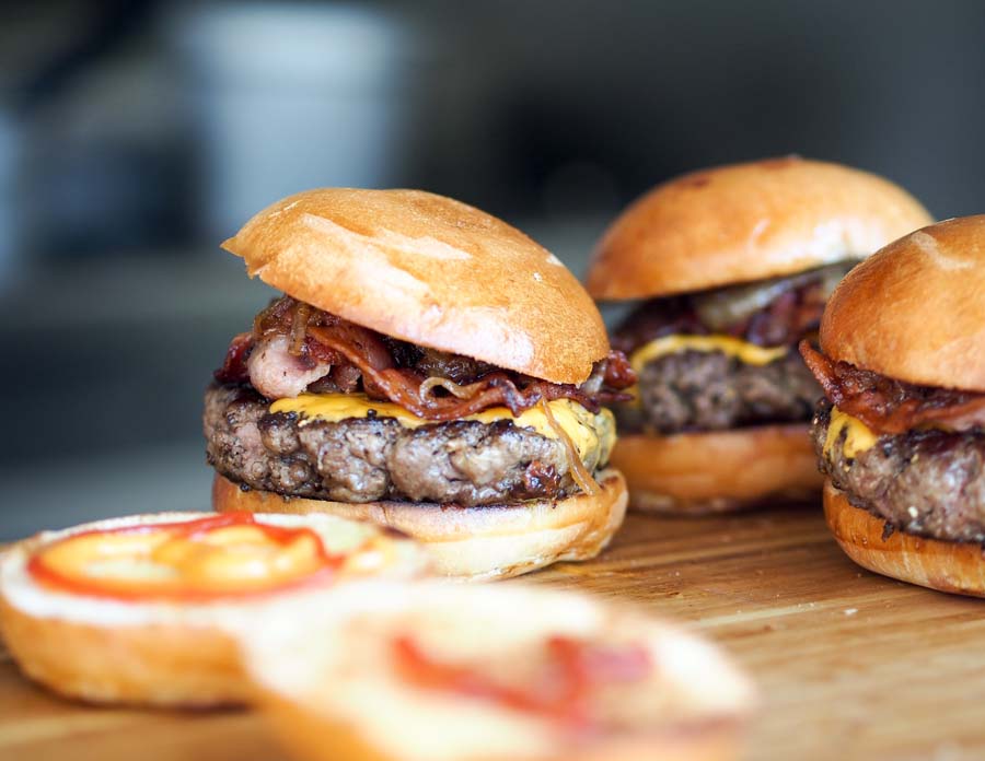 Three cheeseburgers on a wooden table